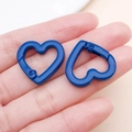 Close-up of two heart-shaped blue metal spring snap hooks held in hand for scale - Dark Blue