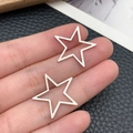 Pair of matte silver hollow star-shaped stainless steel charms held by hand - Pentagram Style (T1890)