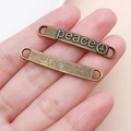 Detailansicht der antiken Bronze-Peace-Verbinder in der Hand zur Größenbestimmung - PEACE Buchstaben (6201)
