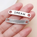 Detail von silbernen Metallanhängern mit Dream-Gravur und strukturierter Oberfläche für Schmuck - DREAM Buchstaben-Tag (5880)