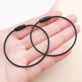 Close-up of two black coated steel wire keyrings held in hand showing screw lock detail - Black