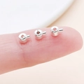 Macro view of tiny silver jewelry crimp beads on a fingertip for size comparison - Flat Bright Silver (19157)