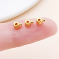 Detailed view of small golden round slider beads for jewelry making held on a fingertip - Flat Imitation Gold (19159)
