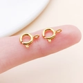Macro view of two 6mm gold spring ring clasps for jewelry making on a fingertip - Gold (25919)