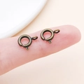 Macro shot of two vintage bronze spring ring clasps on a fingertip for size comparison - Antique Bronze (25916)