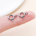 Macro view of gunmetal spring ring clasps for jewelry making held on a finger - Gun Black (25915)