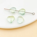 Nahaufnahme der transparenten hellgrünen Glasperlen in Herzform mit Loch für DIY-Schmuckherstellung - Herz Perle / 1 Stück/Packung (10mm) / Transparent Gelbgrün Farbverlauf (26926)