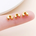 Macro view of gold-plated C-shaped crimp covers shown next to a finger for scale - Large Gold (25599)