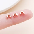 Macro shot of three rose gold crimp bead covers on a finger for DIY jewelry making size scale - Medium Rose Gold (25590)
