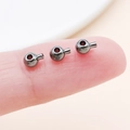 Three gunmetal gray copper jewelry crimp beads held on fingertip for size reference - Round Gun Black (25907)