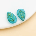 Close-up of green leaf-shaped glass beads with golden leaf veins for DIY hair accessories - Transparent Lake Blue Gold Veined (26682)