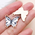 Détail d'un pendentif papillon en alliage avec motif émaillé blanc et dos texturé - Papillon Imprimé (24883)