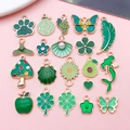 Selection of green enamel clover and cat paw alloy charms on a pink background - Enamel Green 20 Styles Set (SN1643)