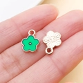 Green enamel flower charms with golden metal sunburst texture held between fingers - Green Enamel Flower Pendant (12350)