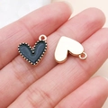 Pendentif coeur émaillé noir avec bordure dorée et dos poli posé sur un bout de doigt - Cœur de Pêche (14984)