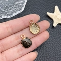 Charm coquillage DIY avec face émaillée noire et dos grillagé doré tenu dans la main - 13x19mm / Coquillage (8604)