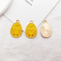 Detail of yellow enamel chick pendants with gold metal frames and textured back surface - Chick Egg