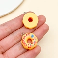 Macro view of realistic resin donut charms with chocolate text and colorful sprinkles - Yellow (23859)