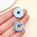 Detail of a blue resin donut charm with chocolate text and colorful sprinkles on hand - Lake Blue (23855)