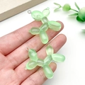 Detailweergave van twee lichtgroene hars ballonhond-hangers in de hand gehouden - Glitter Groene Ballonhond Stijl (23904)