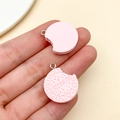 Detail of pink resin biscuit charms with BISCUITS engraving held by hand for DIY crafts - Pink Letter Sandwich Cookie