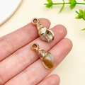 Golden rimmed conch shell pendants held by hand for DIY jewelry and keychain making - Laser Plated Gold Beige Ocean Conch (23617)