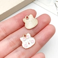 Vue macro de breloques lapin blanc et éventail doré présentées sur un doigt - Lapin Animal en Émail Blanc Or KC (23530)