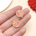 Golden red enamel 'Fu' pendant for DIY bracelets showing product size on hand - Red Enamel Matte Gold Round Double Sided Fu (18459)