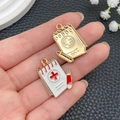 Notebook-shaped alloy pendants with red cross medical symbols and gold finish - White Casebook (23063)