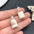 Close-up of mini DIY organic milk bottle charms with metal rings held in hand - Transparent White Milk Bottle (24076)