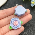 Detail showing blue and pink resin camellia flower charms with green leaves and metal loops - Blue(24607)