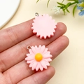 Macro detail of a pink resin daisy charm with a yellow center and silver metal hanging ring - Pink (24598)
