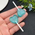Dettaglio di due ciondoli lecca-lecca a cuore in resina glitter blu con ganci argento - Blu Lago Trasparente (24553)