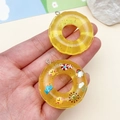 Detail van schattige hars donuthangers met glitters en cartoonpatronen voor DIY-projecten - Transparant Geel