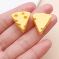 Detailed view of two miniature yellow resin cheese charms held in palm for DIY jewelry - Yellow Triangle Cheese (24651)