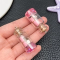 Dettaglio di mini bottiglie dei desideri DIY con rotoli rosa e base glitterata - Rosa Trasparente (24168)