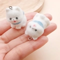 Detail showing two miniature white flocked dog charms held in hand for size context - 30x19x24mm / White Resin Flocked Puppy Scarf (24796)