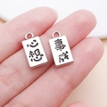 Close-up of rectangular silver pendants with lucky Chinese characters on fingertips - May All Wishes Come True (Antique Silver)