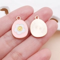 Pink enamel Easter egg charm with a smiley flower and textured golden metal back - Pink Easter Frangipani Egg (25127)