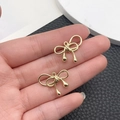 Detalle de colgantes de metal dorado con forma de lazo para creación de joyas DIY - Lazo Envuelto (21404)