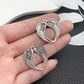 Close-up of retro silver angel wing pendants with heart-shaped hollow design held by hand - Antique Silver Heart Shaped Wing (21423)