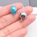 Nahaufnahme von blauen Emaille- und Silberperlen zwischen Fingern für die Größe - Blauer Strass Kugelfisch Fisch Perle (19828)
