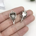 Gros plan de pendentifs tête d'oiseau argentés vintage sur une main pour l'échelle - Tête d'Oiseau Crâne Argent Antique 14x30 (15552)