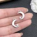 Pair of silver star and crescent moon pendants shown on a finger for size reference - Antique Silver Moon Star 11x17mm (8519)