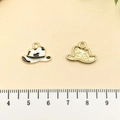 Vue macro d'un pendentif chapeau de cowboy en émail imprimé vache et finition dorée - Chapeau Cowboy Western Émail Blanc Alliage Or (21854)