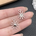 Silver starburst charms with hanging loops held on fingertips to show small size - Antique Silver Sun 18x14mm (21507)