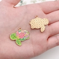 Detailed view of turtle enamel charms with floral painting held in hand for DIY jewelry - Green Flower Turtle