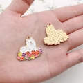 Detailed palm view of an enamel dog charm surrounded by colorful alloy flowers - White Floral Samoyed