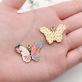 Macro shot of butterfly pendant with enamel floral front and golden mesh texture back - Pink Flower Butterfly