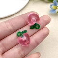 Close-up of pink translucent peach resin pendants with green leaves for DIY jewelry making - Pink Apple (22167)